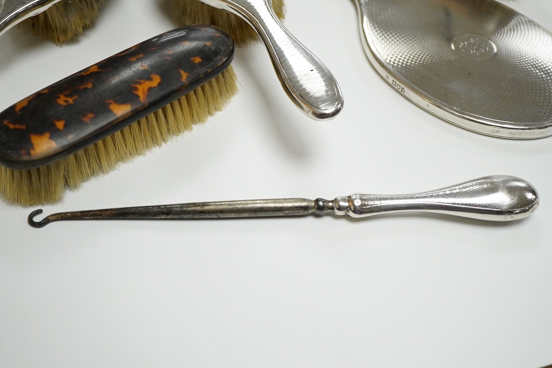 A George V seven piece silver mounted toilet set by Charles Henry Dumenil, comprising a hand mirror, four brushes, a glass toilet jar and button hook, London, 1911/12 & 18, together with one other silver mounted toilet j